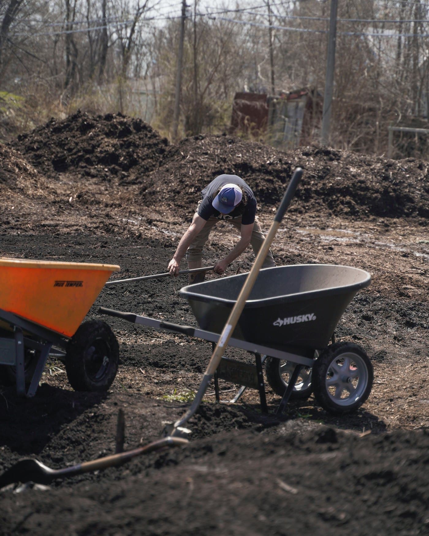 Landscaper moving soil between wheelbarrows on a property under maintenance